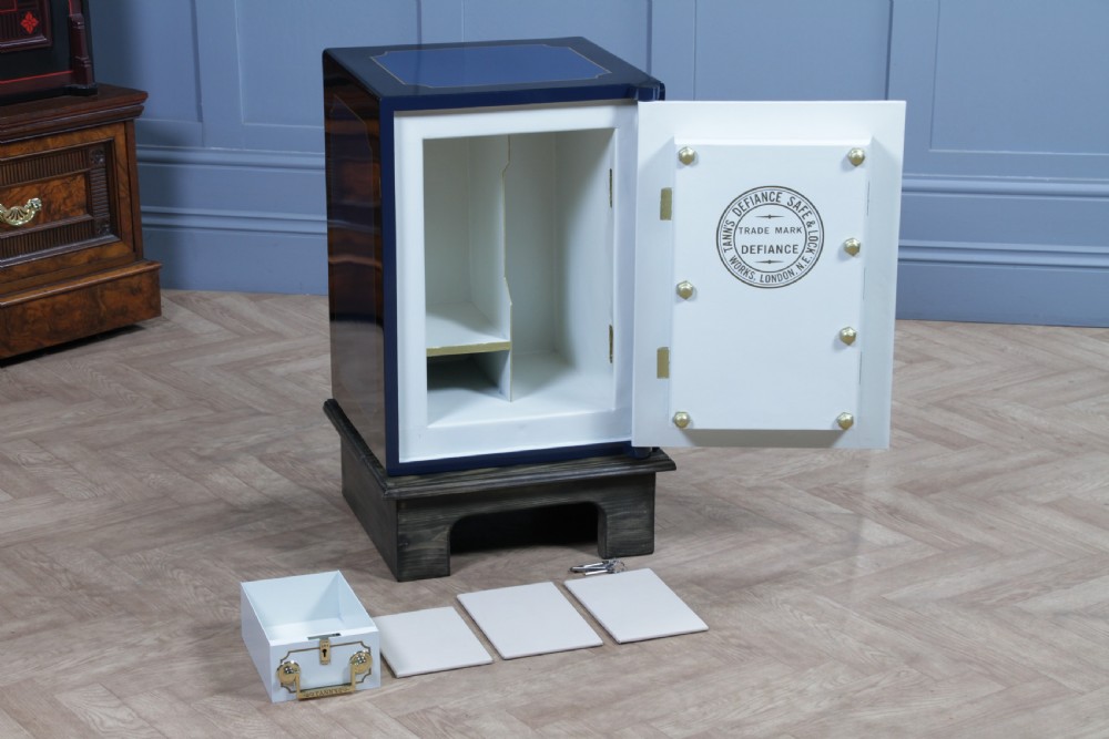 A restored Victorian navy blue and black cast iron safe featuring polished brass hardware and a makers plaque, raised on a dark wooden plinth. View X