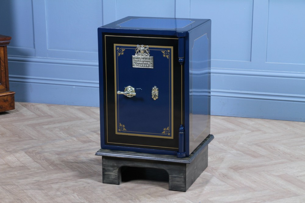 A restored Victorian navy blue and black cast iron safe featuring polished brass hardware and a makers plaque, raised on a dark wooden plinth. View XX