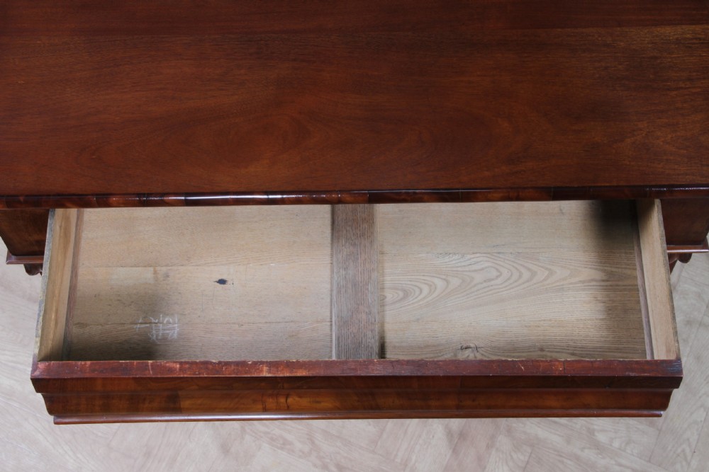 A Victorian flame mahogany two-door sideboard featuring a cushion drawer, arched panel doors, carved corbels, and turned bun feet. View VIII