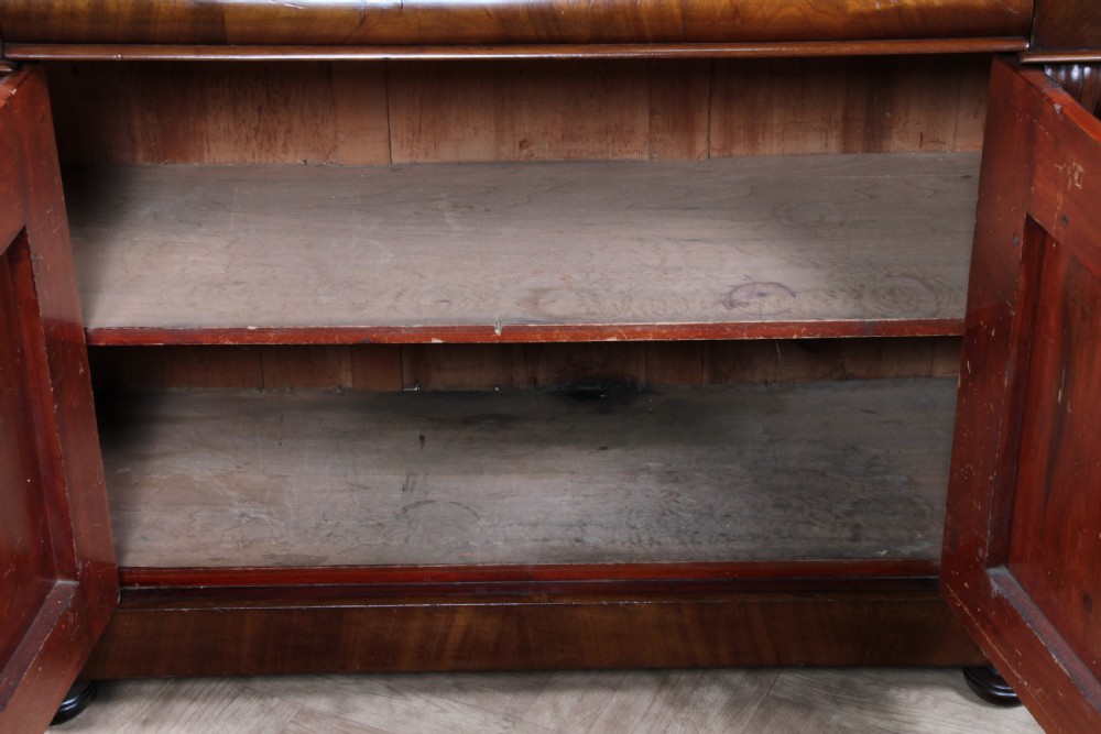 A Victorian flame mahogany two-door sideboard featuring a cushion drawer, arched panel doors, carved corbels, and turned bun feet. View IX