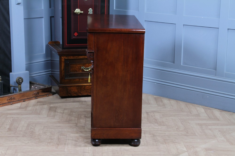 A Victorian flame mahogany two-door sideboard featuring a cushion drawer, arched panel doors, carved corbels, and turned bun feet. View XXI