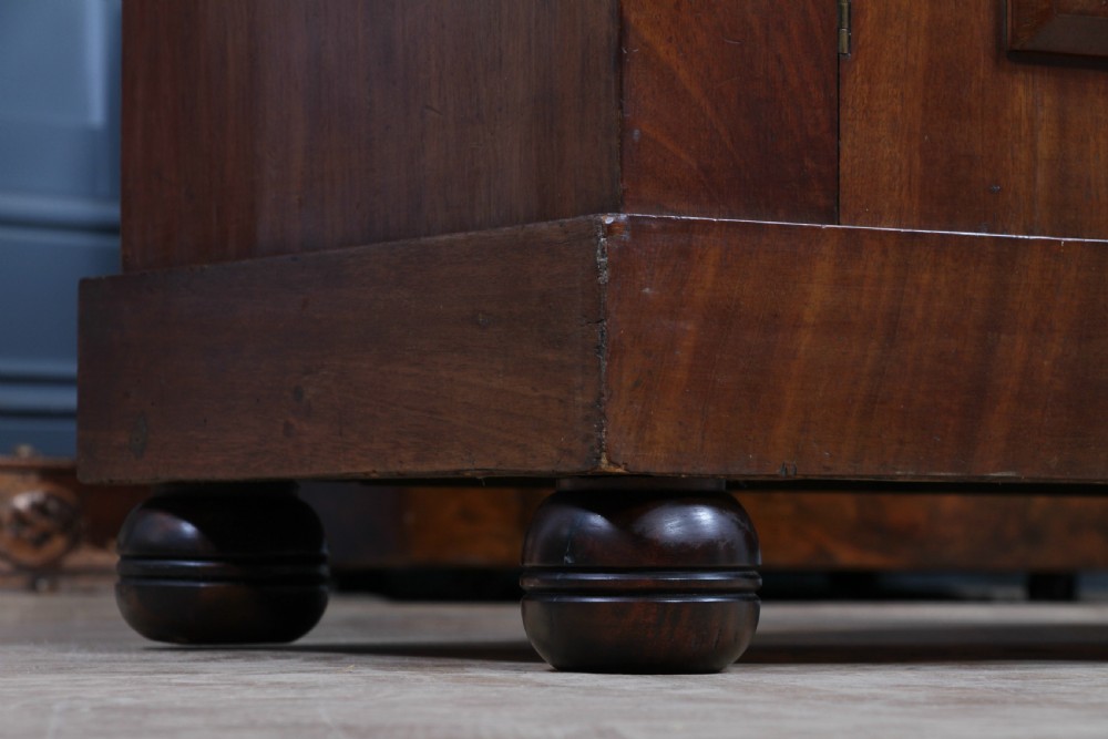 A Victorian flame mahogany two-door sideboard featuring a cushion drawer, arched panel doors, carved corbels, and turned bun feet. View XXII