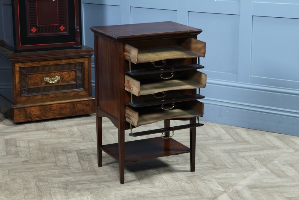 An Edwardian mahogany music cabinet featuring five drop-front drawers with brass handles and a lower open shelf.