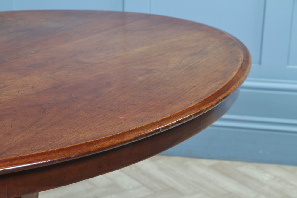 A Victorian oval mahogany tilt-top dining table supported by an octagonal column and a carved tripod base with brass castors. View XVII