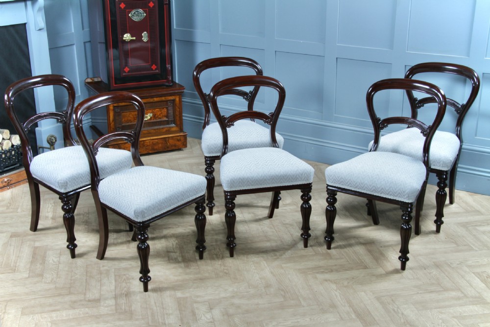 A set of six Victorian mahogany balloon back dining chairs featuring turned front legs and light grey chevron-patterned upholstered seats.