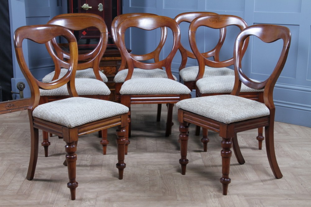 A set of eight Victorian mahogany dining chairs featuring open rounded balloon backs, turned front legs, and neutral patterned upholstered seats. View III