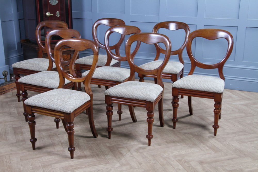 A set of eight Victorian mahogany dining chairs featuring open rounded balloon backs, turned front legs, and neutral patterned upholstered seats. View VIII