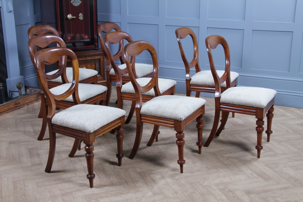 A set of eight Victorian mahogany dining chairs featuring open rounded balloon backs, turned front legs, and neutral patterned upholstered seats. View IX