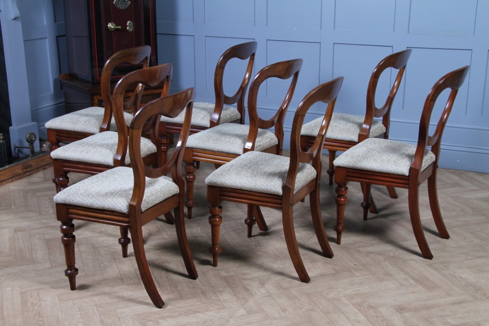 A set of eight Victorian mahogany dining chairs featuring open rounded balloon backs, turned front legs, and neutral patterned upholstered seats. View XI