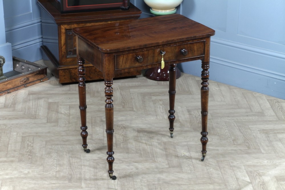 A small Georgian flame mahogany side table featuring a single drawer with turned knobs, ring-turned legs, and brass castors.