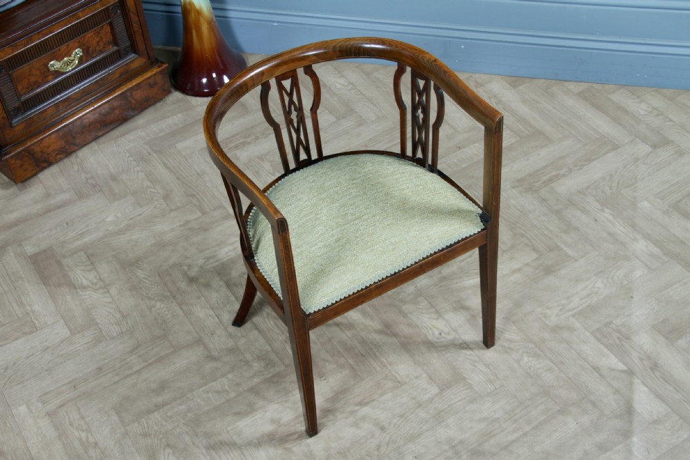 An Edwardian inlaid mahogany tub armchair featuring a continuous curved backrest, pierced splats, and a sage green upholstered seat. View III