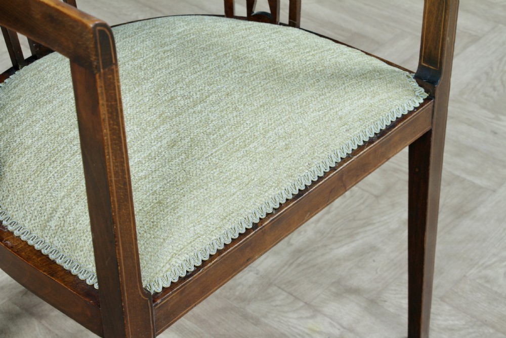 An Edwardian inlaid mahogany tub armchair featuring a continuous curved backrest, pierced splats, and a sage green upholstered seat. View V