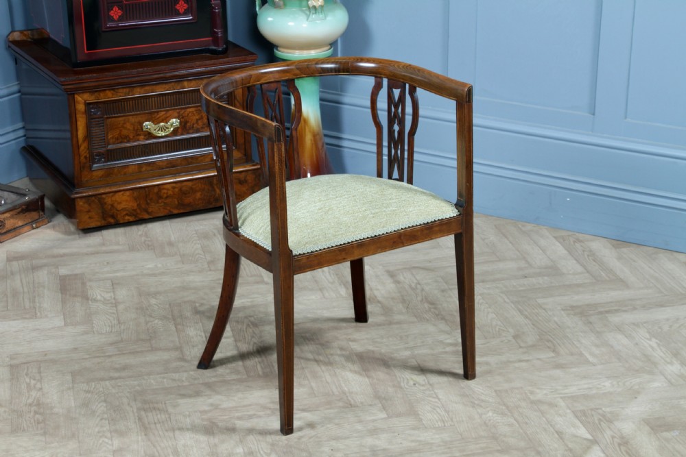 An Edwardian inlaid mahogany tub armchair featuring a continuous curved backrest, pierced splats, and a sage green upholstered seat. View VI