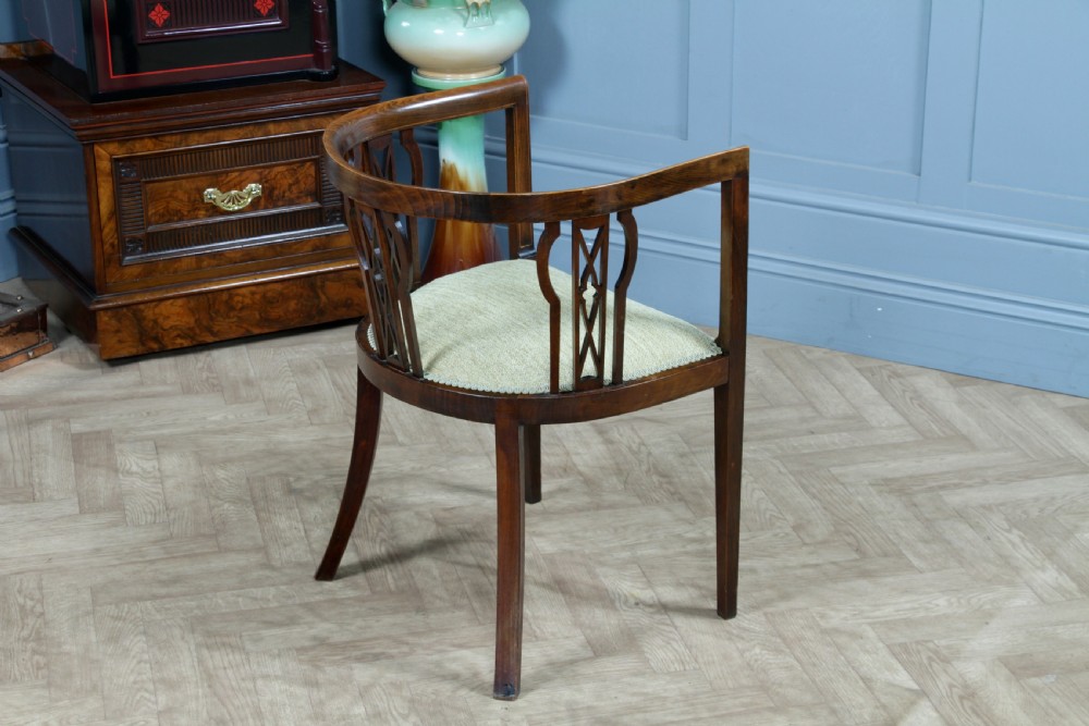 An Edwardian inlaid mahogany tub armchair featuring a continuous curved backrest, pierced splats, and a sage green upholstered seat. View VII