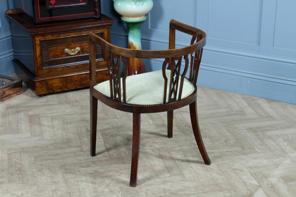An Edwardian inlaid mahogany tub armchair featuring a continuous curved backrest, pierced splats, and a sage green upholstered seat. View VIII