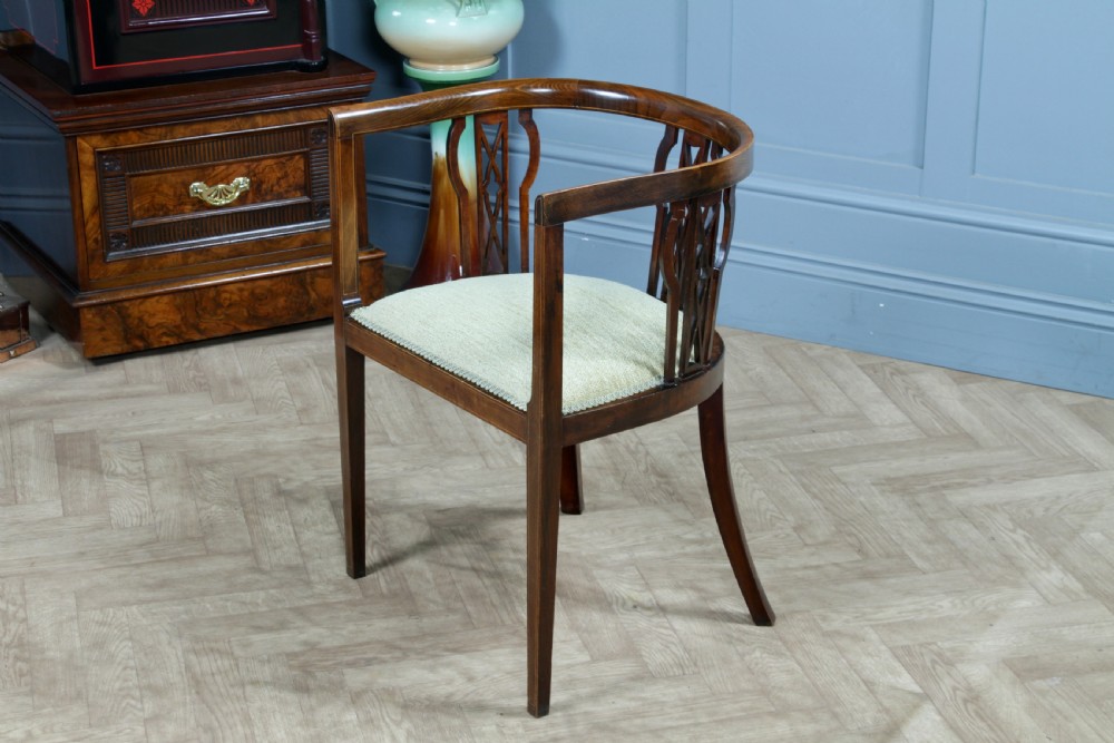An Edwardian inlaid mahogany tub armchair featuring a continuous curved backrest, pierced splats, and a sage green upholstered seat. View IX