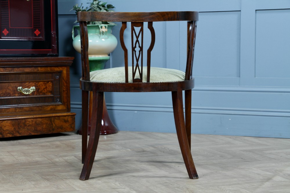 An Edwardian inlaid mahogany tub armchair featuring a continuous curved backrest, pierced splats, and a sage green upholstered seat. View XIII