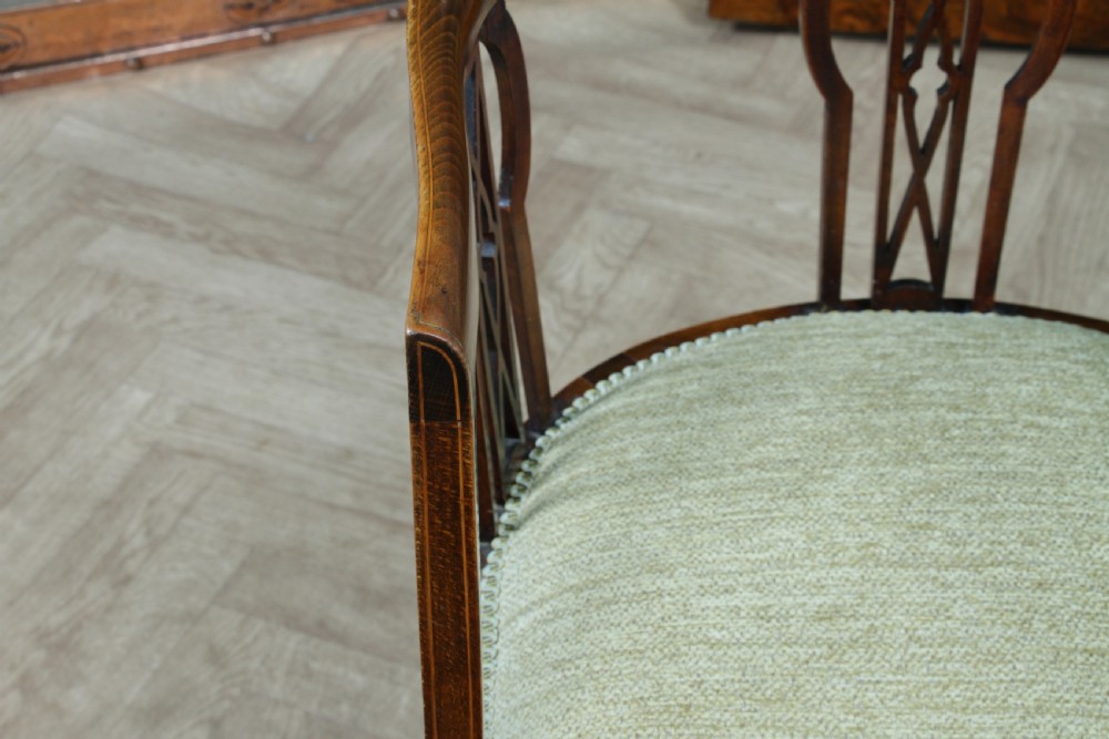 An Edwardian inlaid mahogany tub armchair featuring a continuous curved backrest, pierced splats, and a sage green upholstered seat. View XIV