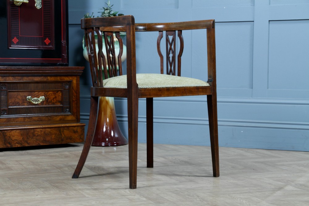 An Edwardian inlaid mahogany tub armchair featuring a continuous curved backrest, pierced splats, and a sage green upholstered seat. View XV