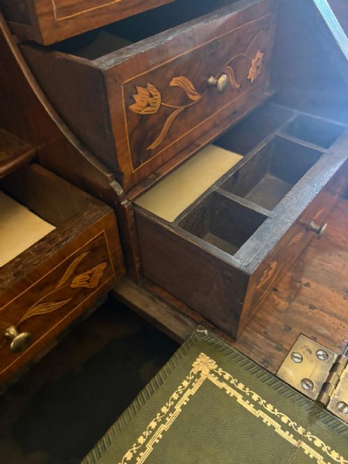 fig 2. An antique Dutch walnut bureau bookcase featuring floral marquetry inlay, a fall-front writing slope, drawers, and an arched glazed display cabinet with tiered side shelves.