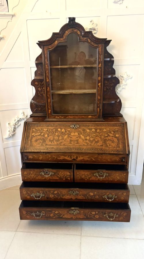 fig 4. An antique Dutch walnut bureau bookcase featuring floral marquetry inlay, a fall-front writing slope, drawers, and an arched glazed display cabinet with tiered side shelves.