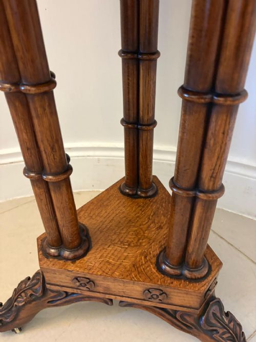 fig 3. An antique hexagonal pollard oak side table featuring a lift-top lid, ring-turned column supports, and a carved tripartite base with castors.