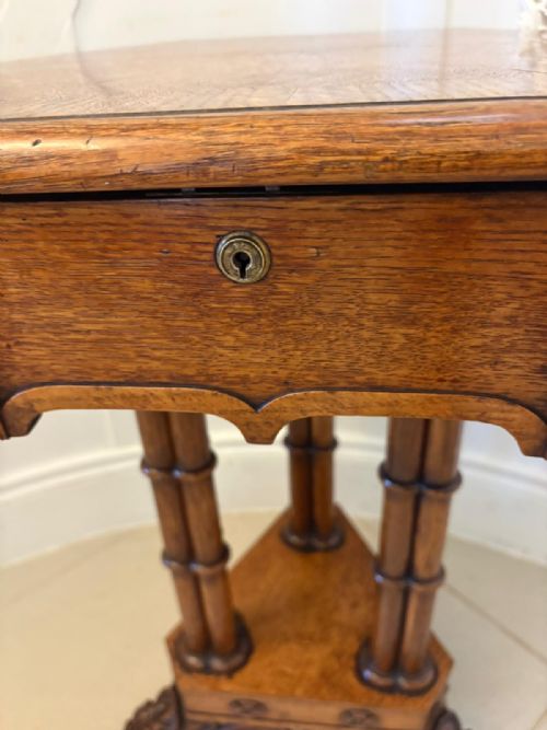 fig 7. An antique hexagonal pollard oak side table featuring a lift-top lid, ring-turned column supports, and a carved tripartite base with castors.