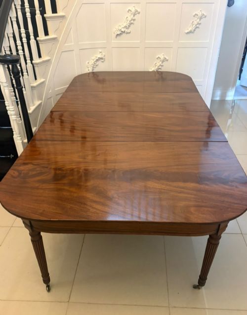 fig 1. A large, polished Regency mahogany extending dining table with rounded corners and reeded legs fitted with brass castors.