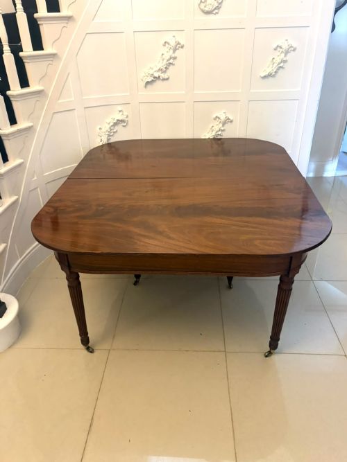 fig 3. A large, polished Regency mahogany extending dining table with rounded corners and reeded legs fitted with brass castors.