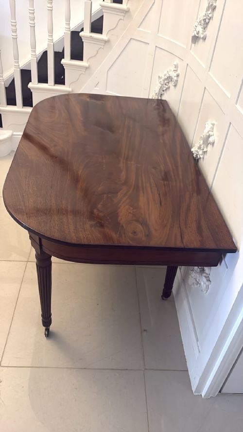 A large, polished Regency mahogany extending dining table with rounded corners and reeded legs fitted with brass castors. View XIII