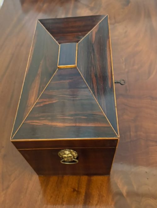 A Regency period dark rosewood tea caddy featuring brass stringing inlay, a faceted lid, and a central keyhole with key inserted. View VII