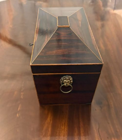 A Regency period dark rosewood tea caddy featuring brass stringing inlay, a faceted lid, and a central keyhole with key inserted. View VIII