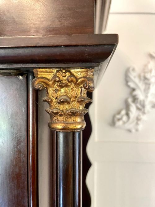fig 6. An antique Victorian dark mahogany longcase clock with a swan-neck pediment, ornate brass dial, arched trunk door, and stepped base.