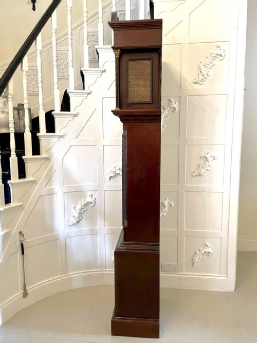fig 8. An antique Victorian dark mahogany longcase clock with a swan-neck pediment, ornate brass dial, arched trunk door, and stepped base.