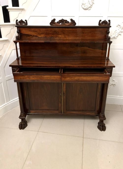 fig 1. A dark mahogany Regency chiffonier sideboard featuring a two-door lower cupboard, turned support columns, carved claw feet, and a raised upper display shelf with a carved scroll cresting.