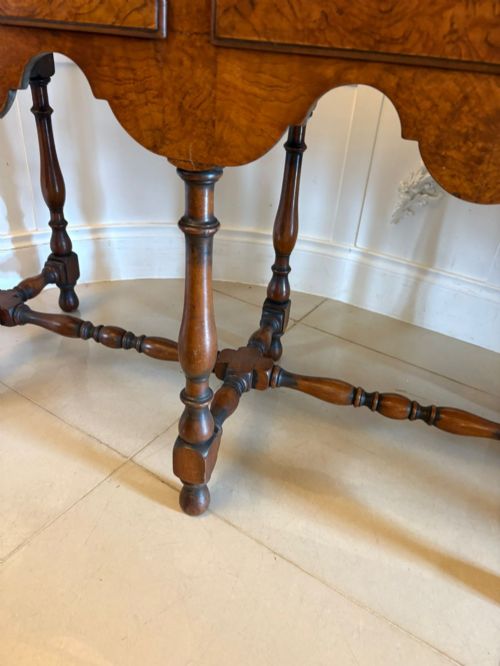 fig 1. An antique Edwardian burr walnut dresser base featuring three drawers, brass drop handles, a scalloped apron, and turned legs connected by stretchers.