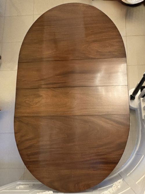 An antique oval extending mahogany dining table on splayed pedestal legs with brass castors. View VI
