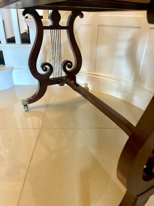 fig 1. An antique Regency mahogany free-standing writing desk featuring a red leather gilt-tooled insert, two frieze drawers, lyre-form end supports, and brass castors.