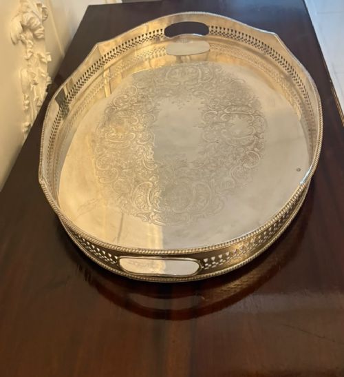 An oval Edwardian silver plated serving tray with an engraved foliate surface pattern and a pierced gallery border featuring cut-out hand grips. View X