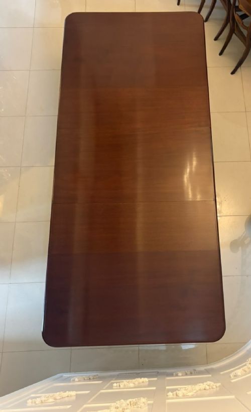 A large William IV figured mahogany extending dining table with a polished surface, rounded corners, and turned legs on brass castors. View XI