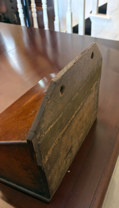 A dark oak Georgian wall-hanging candle box featuring a sloped hinged lid and a shaped backboard with two mounting holes. View VII