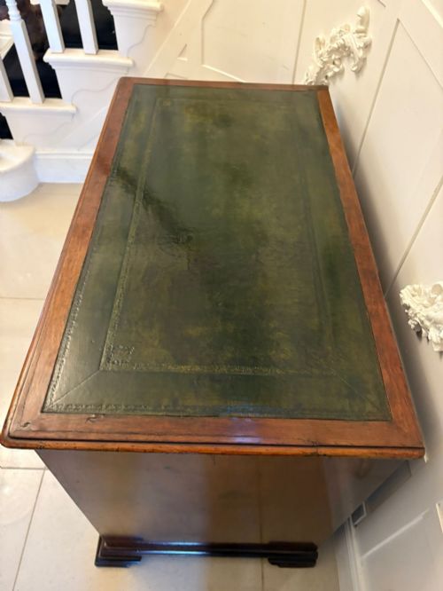 fig 1. An antique George III mahogany kneehole desk featuring a green leather inset top, brass handles, a central recessed cupboard, and multiple drawers set on bracket feet.