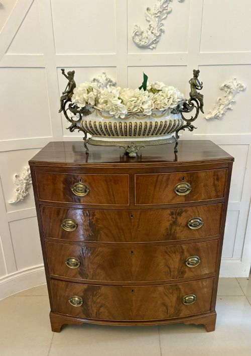 fig 1. A George III mahogany bowfront chest of drawers featuring two short drawers over three long drawers with oval brass handles and splayed bracket feet.