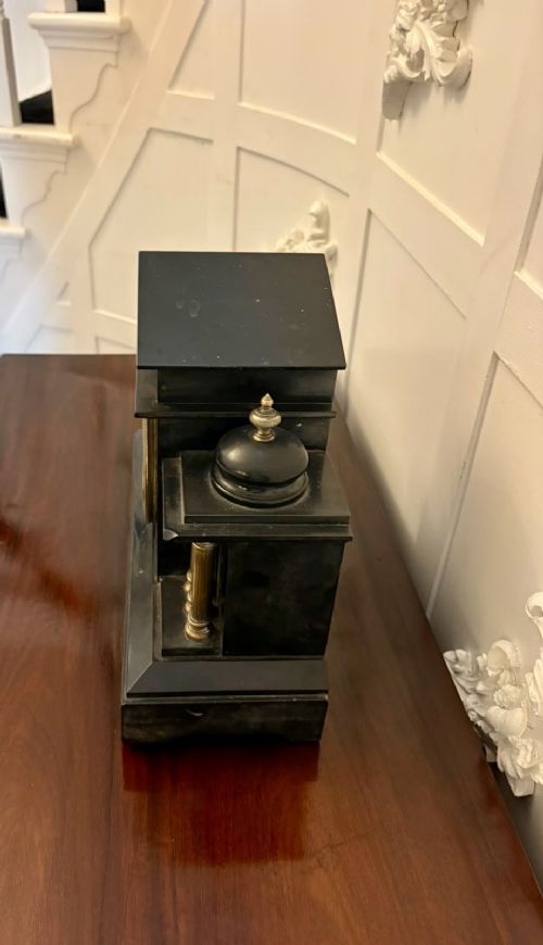 fig 6. An architectural black marble mantel clock featuring gilt brass columns, a relief frieze panel depicting classical figures, and a round dial with Arabic numerals.