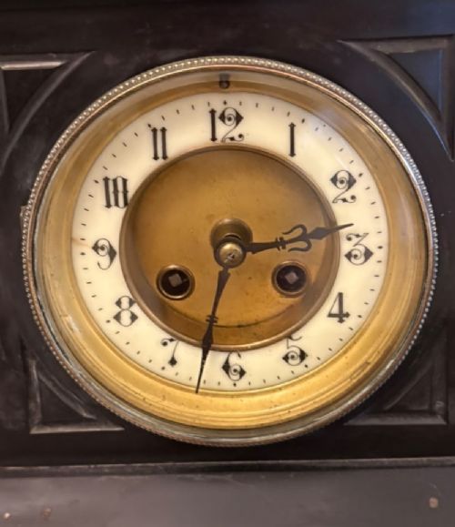 An architectural black marble mantel clock featuring gilt brass columns, a relief frieze panel depicting classical figures, and a round dial with Arabic numerals. View XI