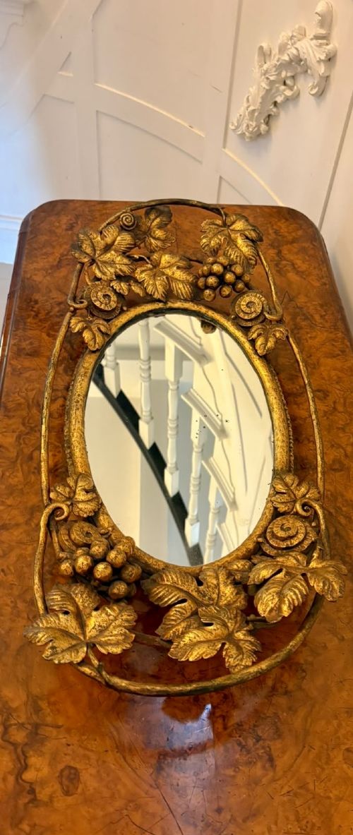 An oval gilt metal tray featuring a central mirror panel surrounded by an ornate border of sculpted grapevines, leaves, and grape clusters. View XI