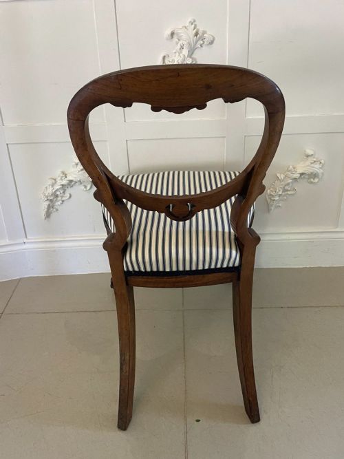 fig 1. A set of six Victorian carved walnut dining chairs featuring rounded balloon backs, carved foliage detailing, cabriole front legs, and blue and white striped upholstered seats.