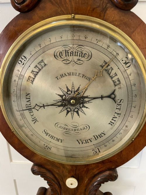 fig 1. Victorian wall-mounted banjo barometer crafted from carved burr walnut featuring an upper glass thermometer gauge and a lower silvered dial in a brass frame.