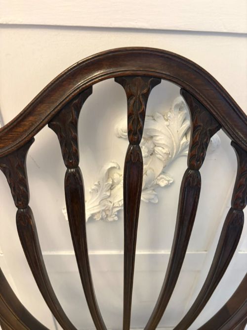 fig 3. A set of ten antique Edwardian mahogany dining chairs featuring carved shield-shaped backrests and light cream upholstered seats.