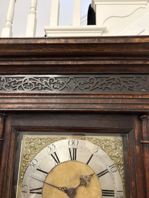 fig 2. A George III oak and burr oak longcase clock featuring a square brass dial, fretwork hood frieze, and a long waist door.
